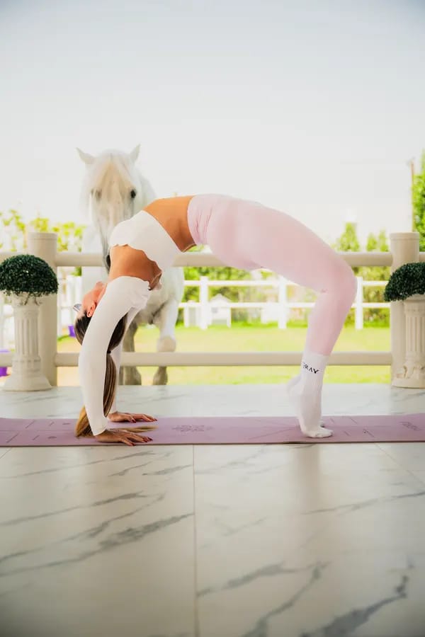 Yoga backbend on platform with white horse at Crystalline Equine